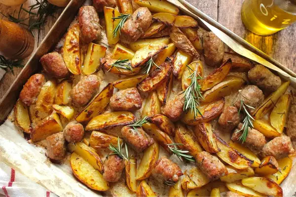 Salsiccia e patate al forno, dorate e profumate al rosmarino, pronte per essere gustate.