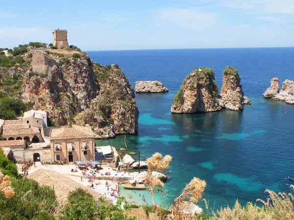 Scogliera con torre a Castellammare del Golfo, mare cristallino e faraglioni.
