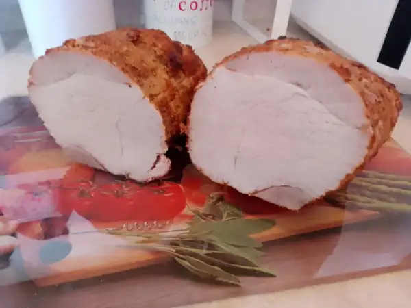 Soczysta szynka pieczona na obiad, pokrojona na pół, z chrupiącą skórką i aromatycznymi ziołami.