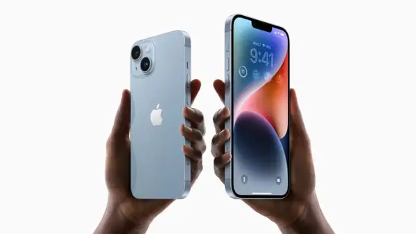 Dwie ręce trzymają jasnoniebieskie iPhone'y 14. Zastanawiasz się, czy oplaca sie kupic iPhone 14?