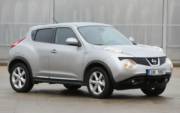 Srebrny Nissan Juke, często chwalony w nissan juke opinie, prezentuje się dynamicznie na tle nowoczesnej architektury.