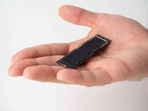 Dłoń trzyma mały dysk SSD M.2. Jego czarna powierzchnia lśni, gotowa do optymalizacji dzięki funkcji ssd trim.
