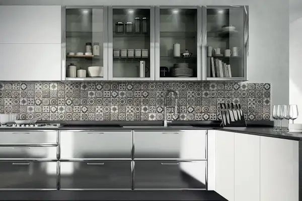 Cucina moderna con ante lucide in acciaio cromato o inox, piastrelle decorate e pensili in vetro.