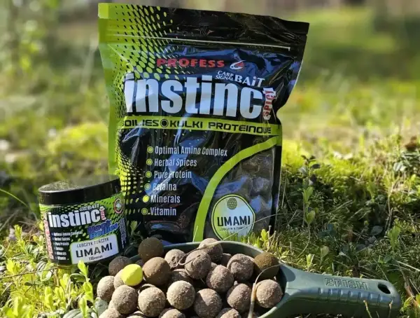 Czeskie kulki proteinowe Instinct Umami w zielonej łopatce, obok opakowania i słoiczka. Idealne na ryby!