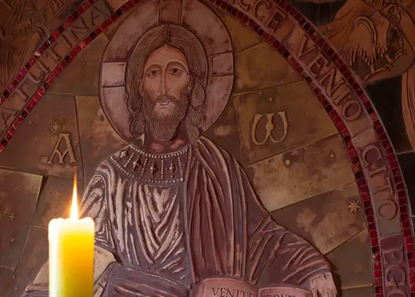 Płaskorzeźba Chrystusa z zapaloną świecą. Wokół napisy, w tym fragmenty nawiązujące do psalmów, np. psalm 99.
