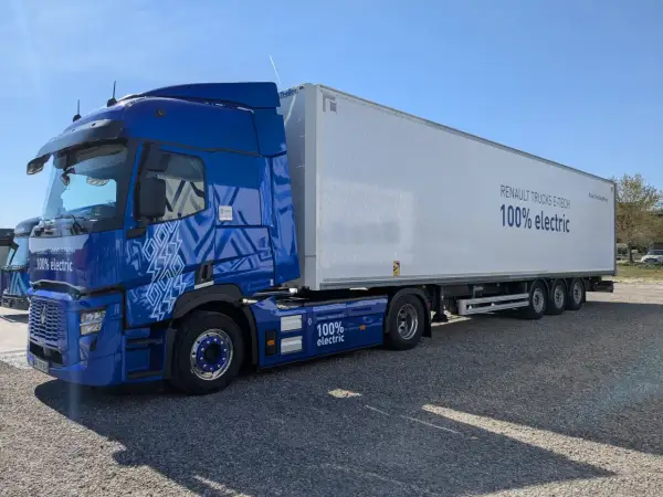 Un camion renault electrique bleu vif, avec une remorque blanche arborant le message "100% electric".