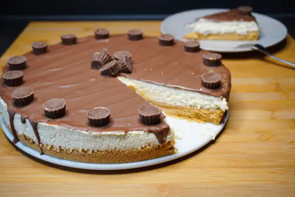 Reese's Torte mit Schokoladenglasur und Erdnussbutter-Cups. Ein Stück ist bereits angeschnitten.