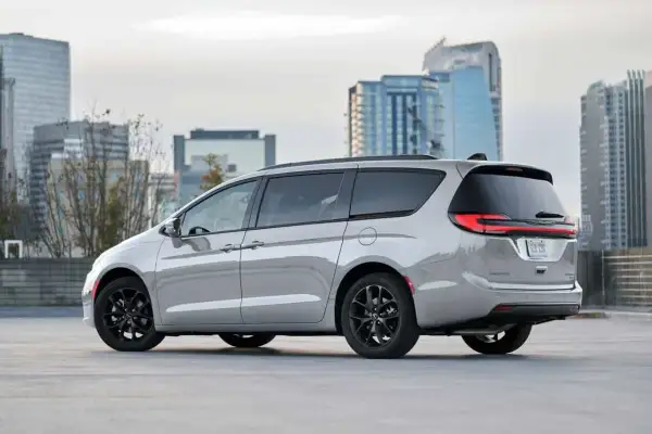 Srebrny Chrysler Pacifica z czarnymi felgami na tle nowoczesnych budynków miejskich.