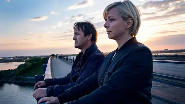 Två personer står på en bro vid solnedgången. En ny dansk serie på Viaplay.