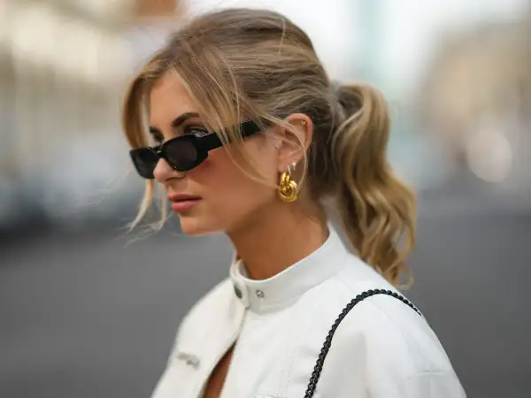 Mujer con coleta y gafas de sol, luciendo un corte de pelo con flequillo cortina que enmarca su rostro.