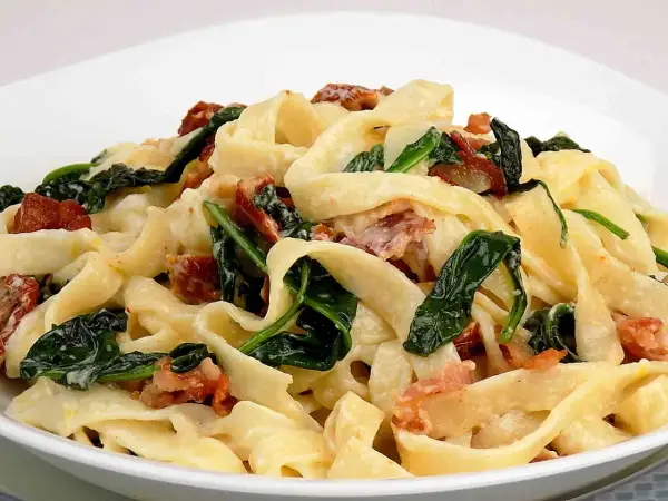 Pyszny makaron tagliatelle z kremowym sosem mascarpone, szpinakiem i chrupiącym boczkiem.