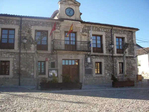 Ayuntamiento de Lozoyuela, con su fachada de piedra, balcón y reloj. Un lugar con mucho que ver.