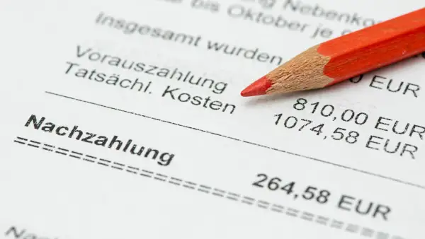 Roter Bleistift auf Nebenkostenabrechnung. Die Nachzahlung ist 264,58 EUR. Fristen für die Nebenkostenabrechnung beachten.