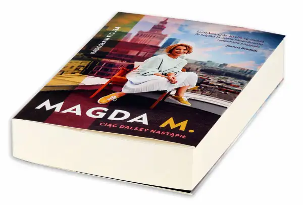 Okładka książki "Magda M. Ciąg dalszy nastąpił" z Radosławem Figurą. Uśmiechnięta Magda M. siedzi na krześle na tle panoramy miasta.