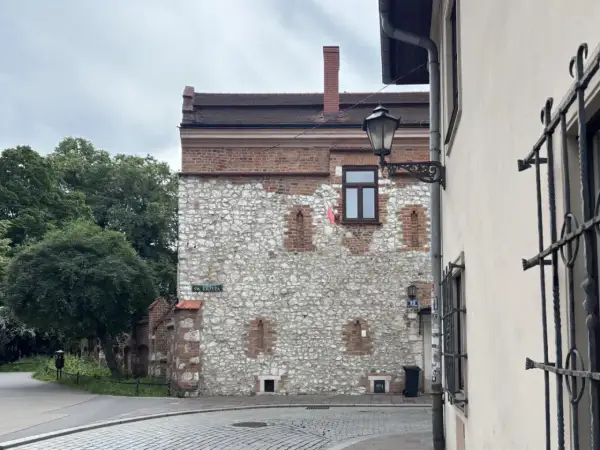 Kamienna ściana z ceglanymi elementami, przypominająca najstarszy dom w Polsce. Ulica Św. Krzyża.