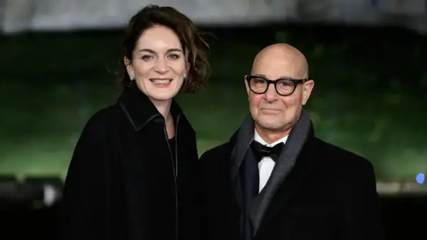 Felicity Blunt y Stanley Tucci sonríen a la cámara, vestidos elegantemente para un evento.