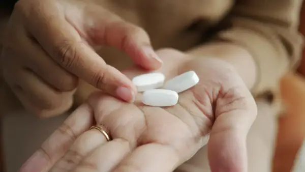 En hand håller tre vita tabletter, kanske för att visa sertralin 25 mg effekt.