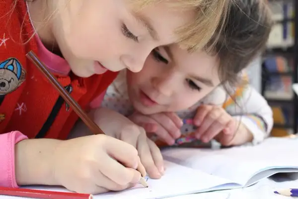 Zwei Kinder lernen gemeinsam an einer Lerntheke Methode, konzentriert auf ihr Heft.
