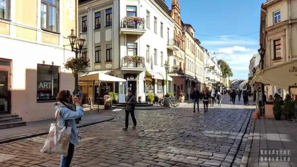 Spacer po urokliwej uliczce w Kownie, gdzie leży to piękne miasto. Kobieta robi zdjęcie zabytkowej kamienicy.