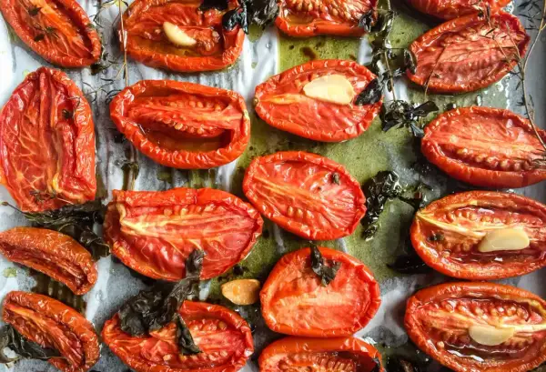 Tomates au four, coupées en deux, rôties avec de l'ail et des herbes, leur chair concentrée et savoureuse.