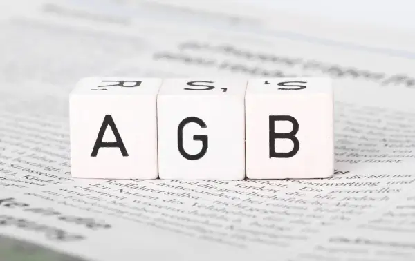 Drei Würfel mit den Buchstaben A, G, B liegen auf Zeitungstext. Ein wichtiger Schritt, um AGB zu erstellen.