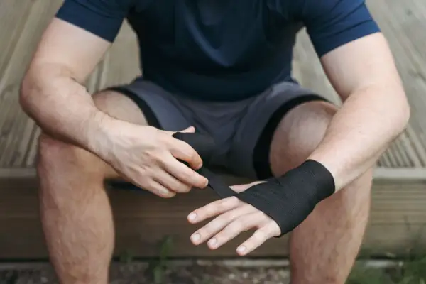 A boxer wraps his hands, ensuring the wraps are snug but not too tight. This is key to protecting his knuckles and wrists during a fight.