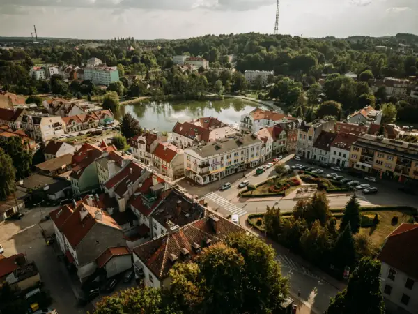 Widok z lotu ptaka na urokliwe Mrągowo. Jezioro, kolorowe kamienice i zielone drzewa tworzą malowniczy krajobraz. Odkryj mrągowo atrakcje!