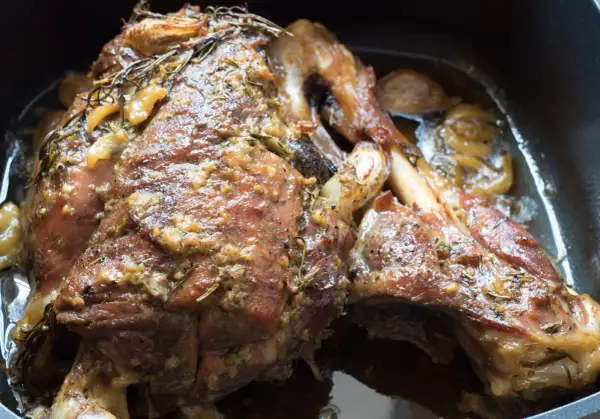 Succulento agnello al forno, dorato e profumato con rosmarino e aglio, pronto per essere gustato.