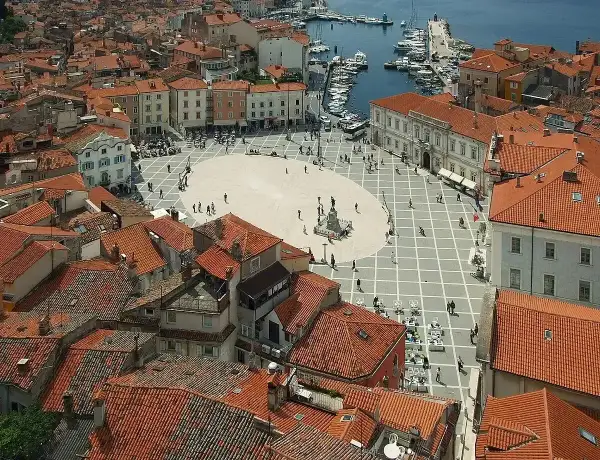 Słowenia morze: malowniczy plac w Piran, z widokiem na dachy i port.