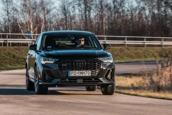 Czarny q3 audi pędzi po drodze, kierowca w okularach obserwuje trasę.