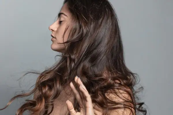 Mujer con ojos cerrados y pelo bonito, moviéndose con el viento.