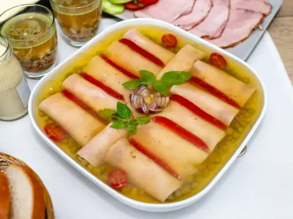 Szynka w galarecie z groszkiem, papryką i pomidorkami. Obok majonez, pieczywo i plastry wędliny.