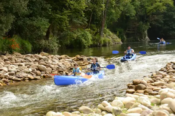Familias disfrutan del kayak por donde pasa el río Sella, rodeados de naturaleza exuberante y aguas cristalinas.