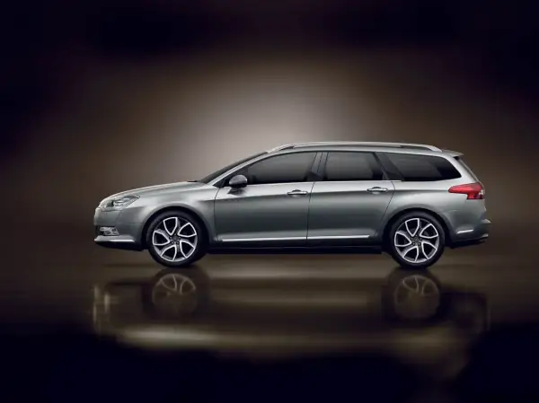 Srebrny Citroen C5 X7 kombi z przyciemnianymi szybami i eleganckimi felgami, odbijający się od błyszczącej powierzchni.
