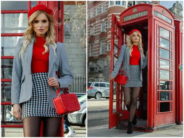 Kobieta w czerwonym beretcie i kratkowanej spódniczce pozuje przy budce telefonicznej, tworząc klasyczny london look.