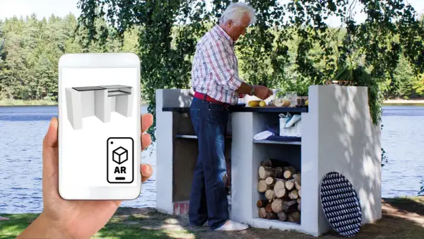 En man förbereder mat vid en murad grill vid en sjö. En telefon visar en 3D-modell av en Murad grill i AR.