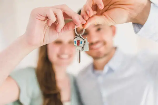 Coppia felice mostra le chiavi di casa, un promemoria delle 10 cose da sapere prima di comprare casa.