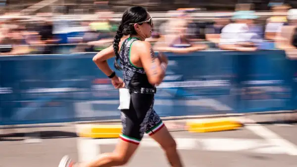 A woman in a triathlon suit, her hair in braids, runs with determination. This is the essence of Ironman training.