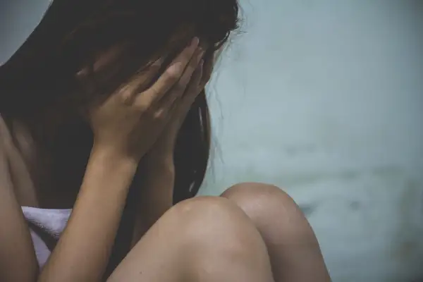 Kobieta ukrywa twarz w dłoniach, przygnębiona. Może to być związane z wypowiedzeniem umowy o pracę a zwolnieniem lekarskim od psychiatry.