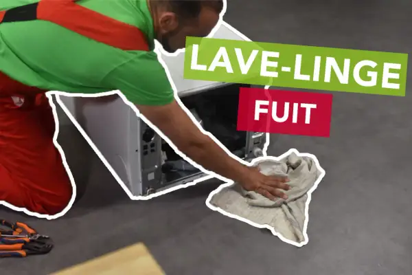 Un tecnico con tuta rossa e verde asciuga con uno straccio il pavimento dove la lavatrice perde acqua dal cestello.