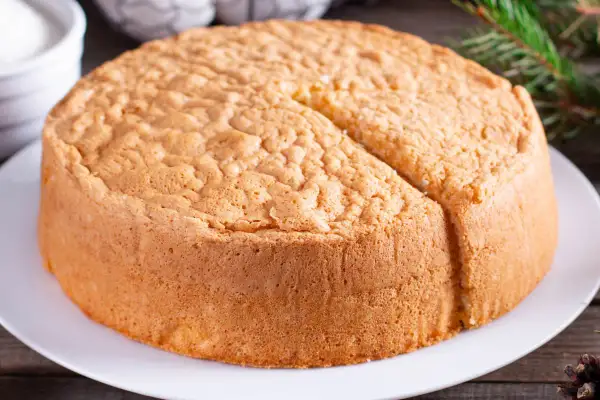 Un soffice angel cake altissima, pronto per essere decorato. La sua consistenza ariosa promette un sapore leggero e delizioso.