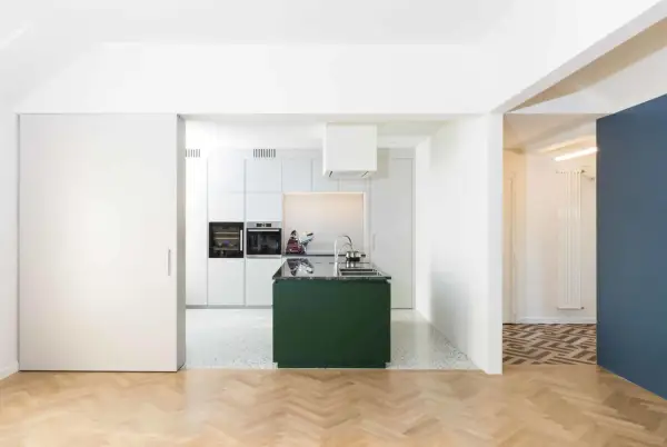 Moderna cucina verde in un ampio soggiorno open space. Pavimenti in parquet e resina, elettrodomestici a scomparsa.