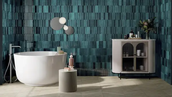 Une salle de bain moderne avec des carreaux muraux bleu sarcelle profonds, une baignoire îlot blanche et un meuble de rangement élégant. Une belle idée couleur salle de bain pour une ambiance chic.