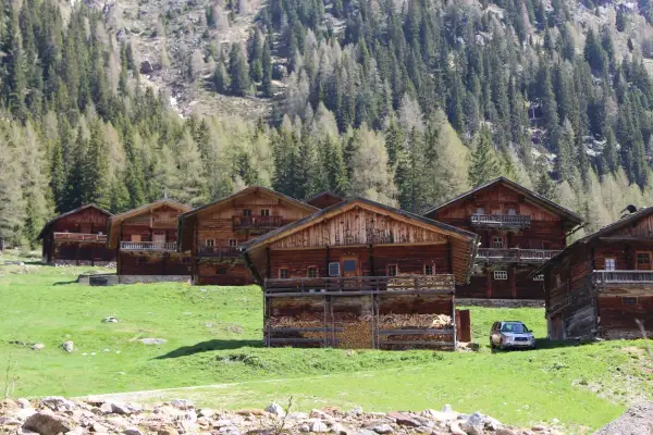 Holzhäuser im Villgratental, umgeben von grünen Wiesen und Nadelwäldern. Eine Karte des Villgratentals würde diese idyllische Landschaft zeigen.