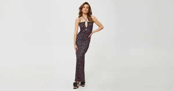 Kobieca sukienka maxi w drobne czerwone kwiatki, idealna do letnich stylizacji. Dekolt typu halter i wycięcie dodają jej charakteru.