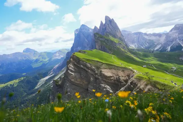 Grönt, blommande landskap i Val Gardena med dramatiska bergstoppar och en slingrande stig.