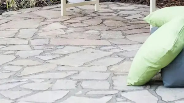 Naturalny chodnik z płyt chodnikowych, idealny do relaksu na świeżym powietrzu. Dwie poduszki, jedna jasnozielona, dodają koloru.