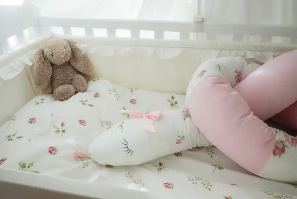 En söt sovorm med blomstermönster och en nalle i en spjälsäng.