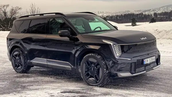 Svart Kia EV9 på en snöig väg, redo för ett vintertest. Bilen har en modern design med distinkta LED-lampor.