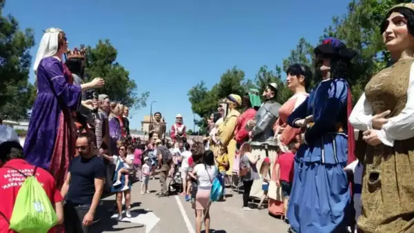 Gigantes y cabezudos desfilan en las fiestas del Parque Goya. Niños y adultos disfrutan de la colorida procesión bajo el sol.